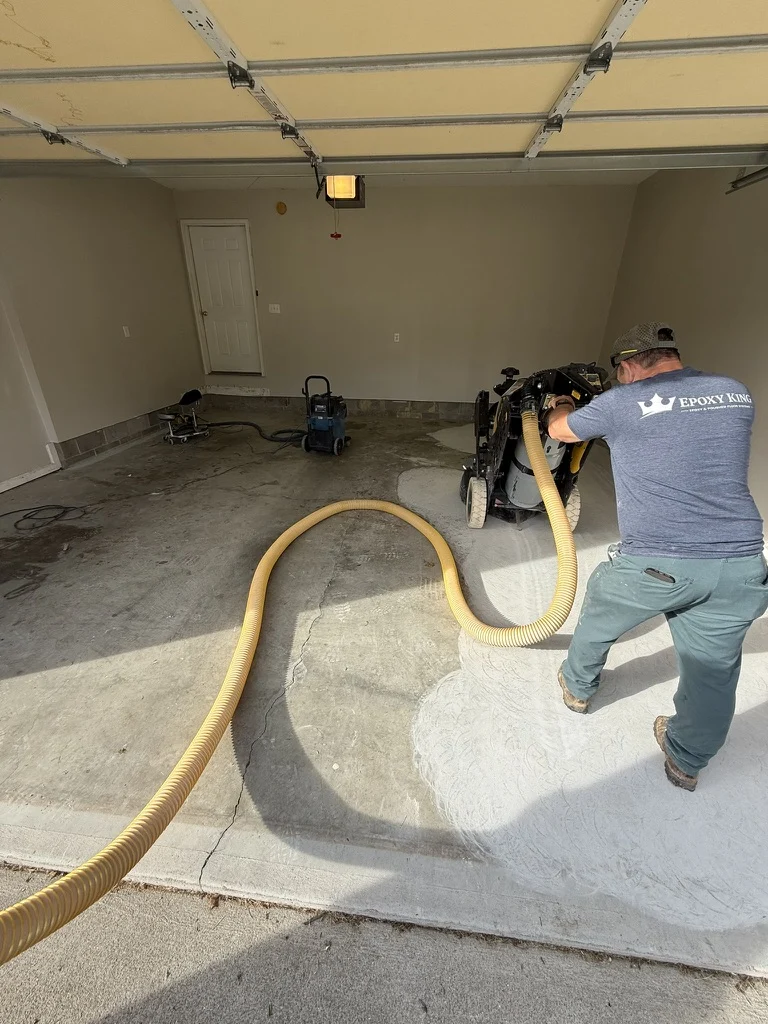 Epoxy King crew member grinding the concrete garage floor with dust-extraction equipment in Princeton, West Virginia