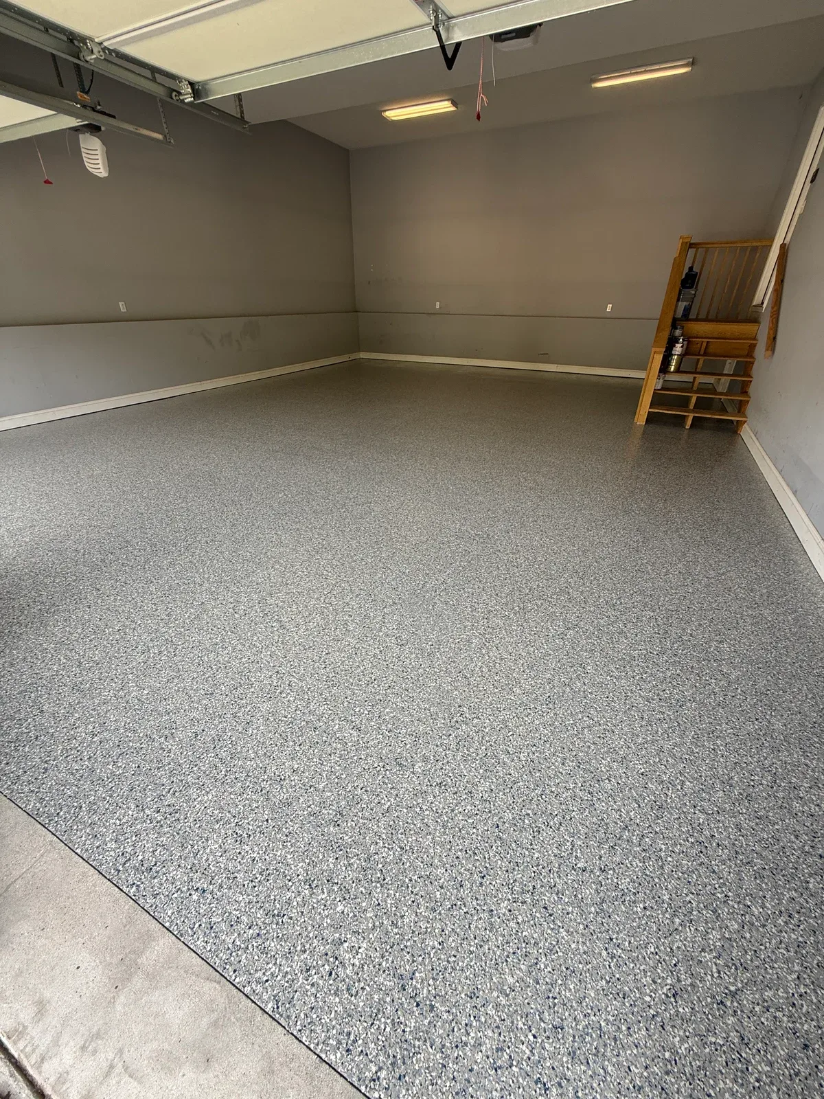 Finished gray decorative-flake garage floor beside wooden entry stairs in Charleston, West Virginia