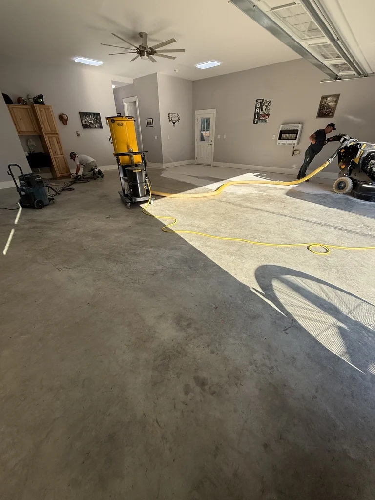 Wide view of concrete grinding and dust-extraction equipment during preparation of the White Sulphur Springs garage
