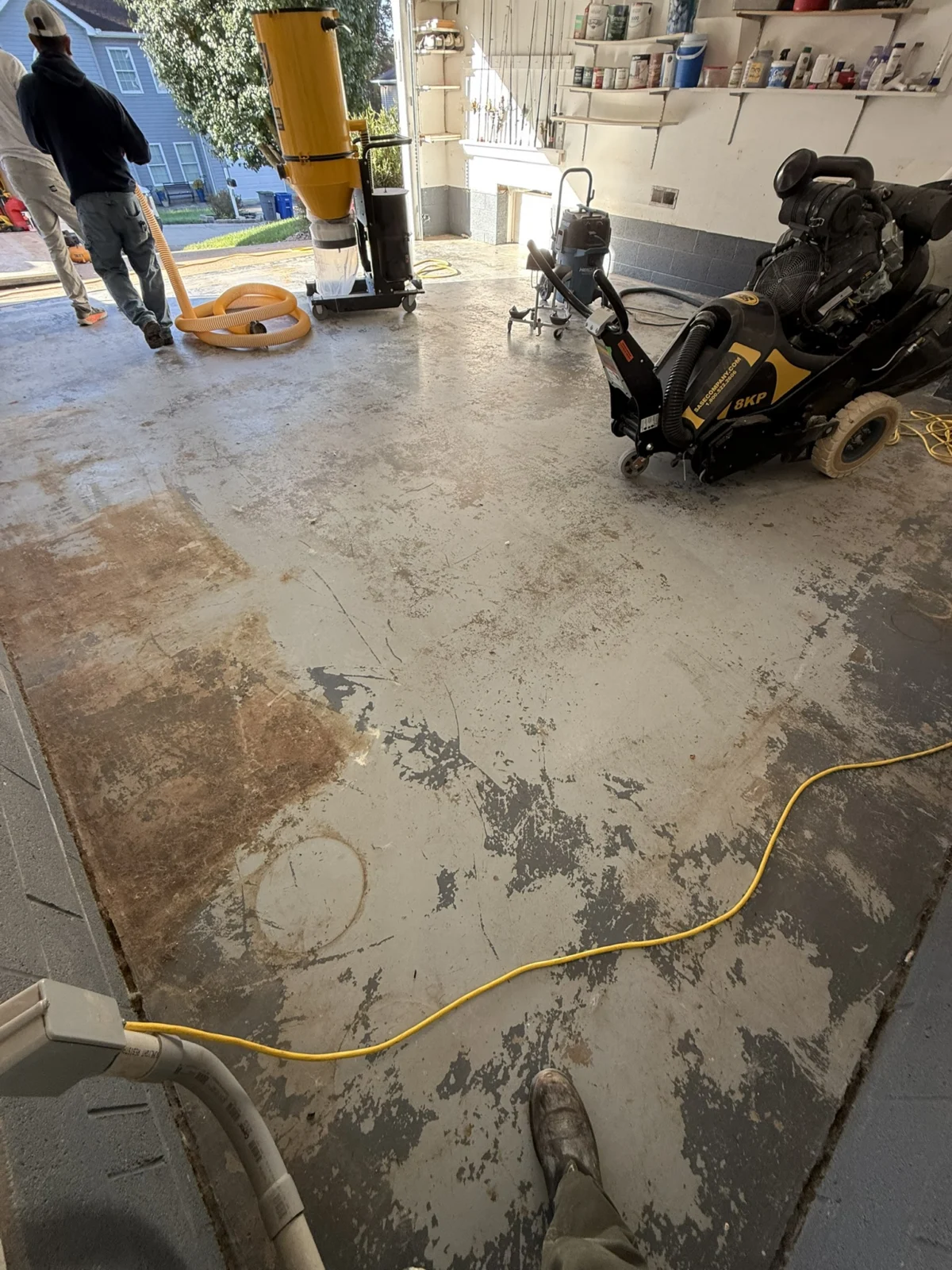 Failed garage coating with planetary grinder and dust collection equipment ready for preparation.