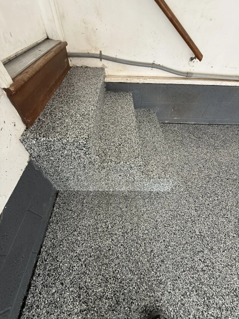 Matching decorative flake coating on the garage entry steps after replacement.
