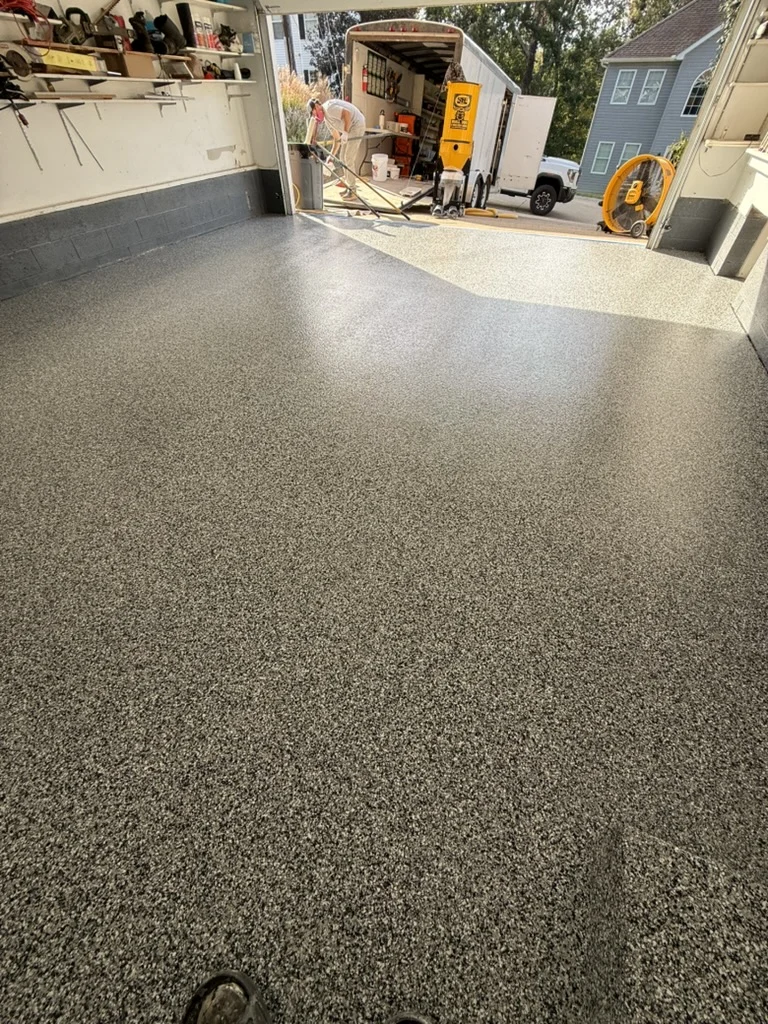 Completed black, white and gray flake garage floor looking toward the open doorway.