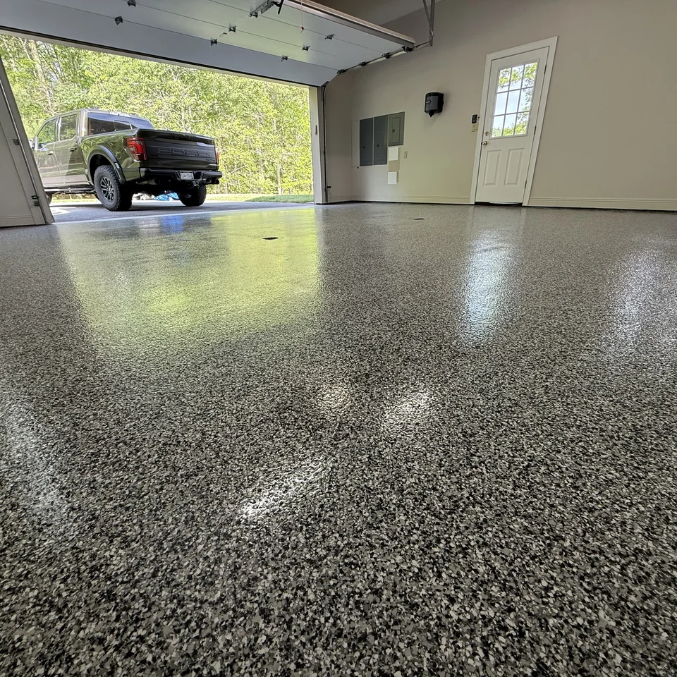 Finished gray decorative-flake garage floor with the garage door open and a pickup outside