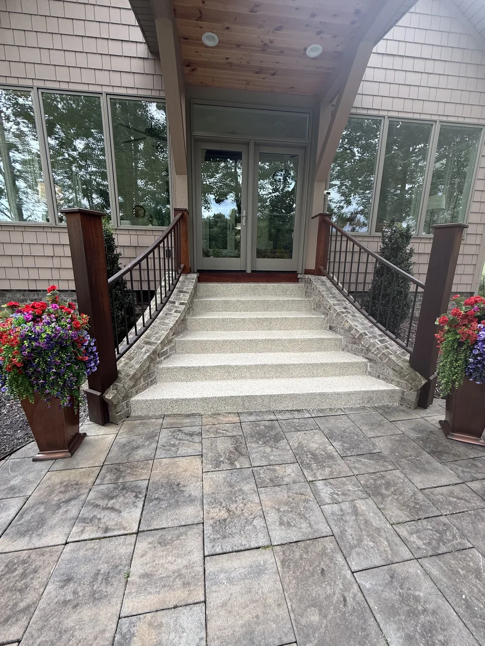 Coated porch steps at a home entrance with brick columns and railings