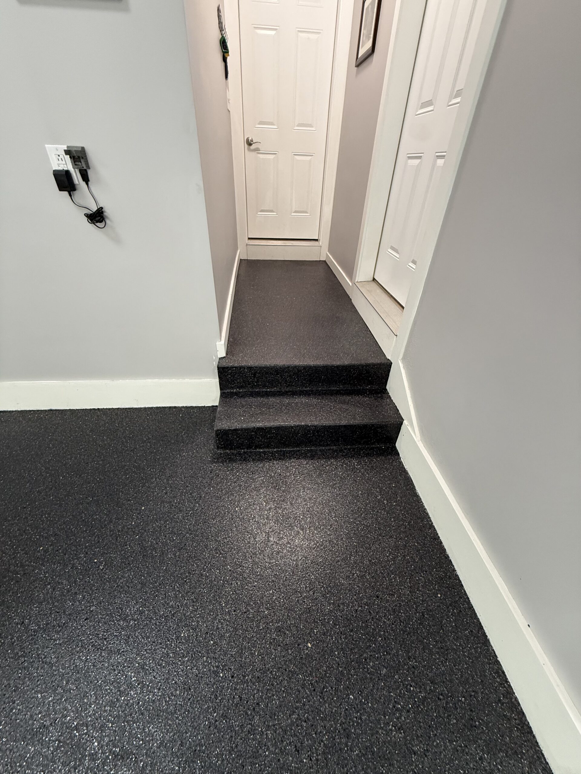 Dark decorative flake floor with coated steps and a landing leading to white doors